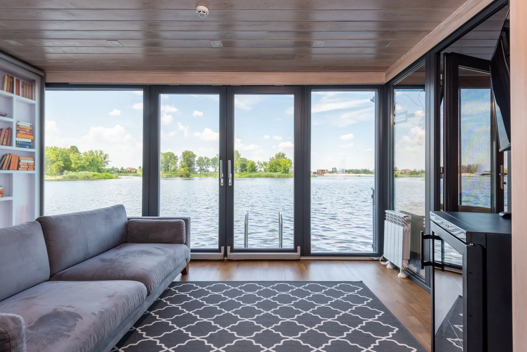 A living room opening onto a lake through glass doors